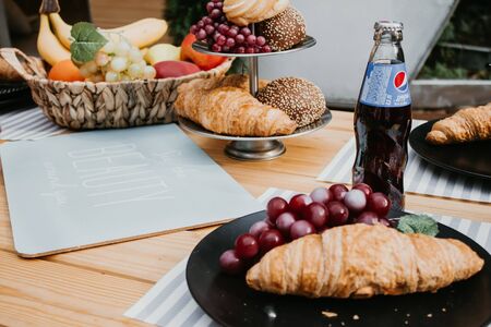 Picnic with croissants, lemonade, Coca Cola and Pepsi ,fruits such as the apple,banana,grape,pear, on a wooden table at the camping.のeditorial素材