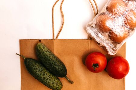 Paper bag with cucumbers, tomatoes, vegetable oil, eggs and canned goods isolated on white background.Food supplies crisis food stock for quarantine.Food delivery, Donation, coronavirus.Tape measureの写真素材