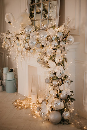 Fireplace decorated with New Years decorations, toys and garlands. Modern New Years decor for the living room and bedroom. Christmas tree, decorated with New Years toys, stands near the fireplaceの写真素材