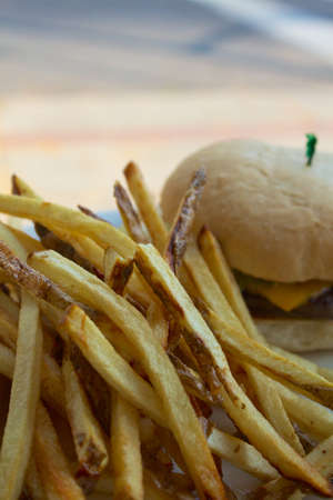 Cheeseburger or hamburger with fries on a white plate 