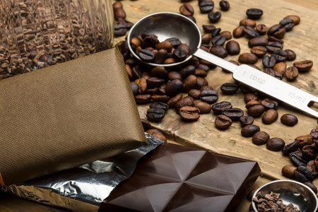Coffee beans and a chocolate bar on a wooden table.