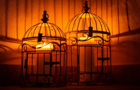 Caged candle lights with shadows on the wallの写真素材