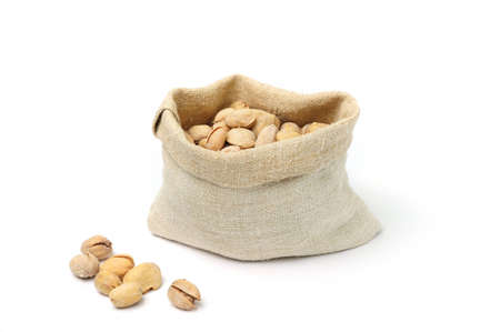 Pistachio in burlap sack on white backgroundの写真素材