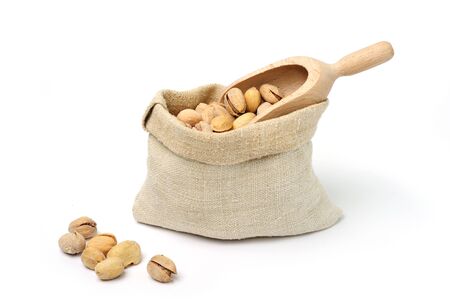 Pistachio in textile sack with scoop on white backgroundの写真素材