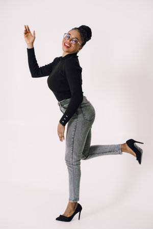 Beautiful attractive African American woman standing and smiling in gray background wearing black...