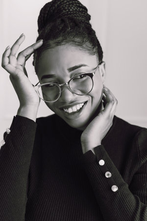 Portrait of beautiful black woman smiling, African American woman wearing black top in black and...