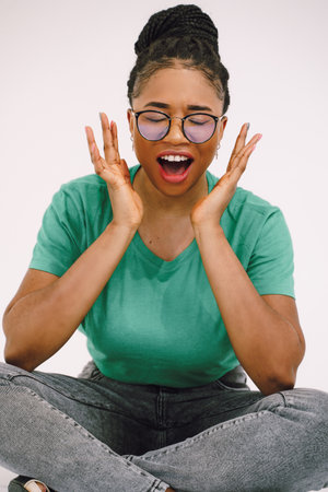 African woman smiling and sitting on the ground in green shirt. Happy black girl with beautiful expressionの写真素材