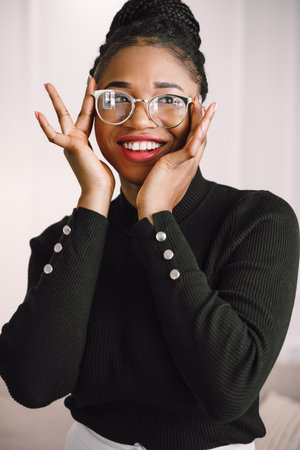 Young beautiful black woman feeling happy and excited in black shirt. Home conceptの写真素材