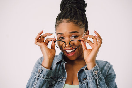 Young attractive African American woman in green dress with jean jacket and smiling in gray backgroundの写真素材