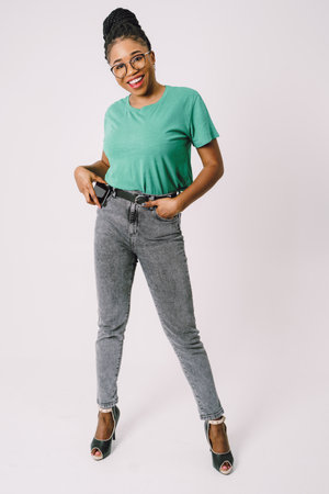 Attractive young African American woman smiling and holding smartphone in gray backgroundの写真素材