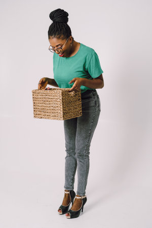 Beautiful African American woman standing holding basket. Happy Black girl in white background, Studio concept of wonderful black girl smiling on white background.の写真素材