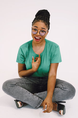 African woman smiling and sitting on the ground in green shirt. Happy black girl with beautiful expressionの写真素材