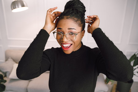 Young beautiful black woman feeling happy and excited in black shirt. Home conceptの写真素材