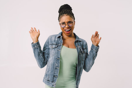 Young attractive African American woman in green dress with jean jacket and smiling in gray backgroundの写真素材