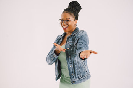 Young attractive African American woman in green dress with jean jacket and smiling in gray backgroundの写真素材
