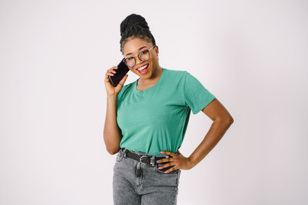 Attractive young African American woman smiling and holding smartphone in gray backgroundの写真素材
