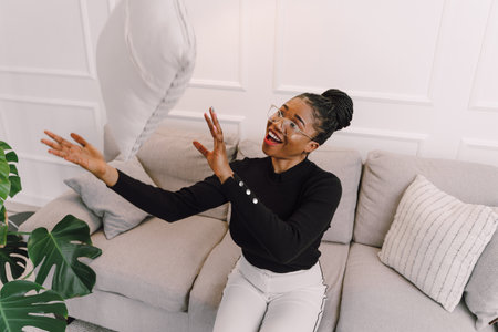 Young beautiful black woman feeling happy and excited in black shirt. Home conceptの写真素材