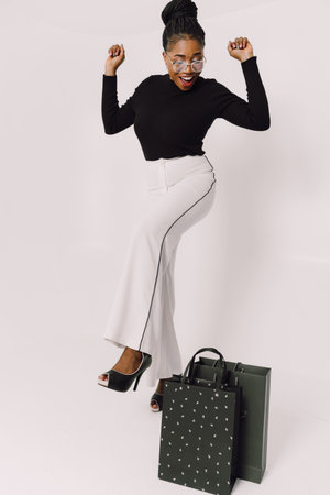 Beautiful young African American woman with shopping bags in green shirt and in gray backgroundの写真素材