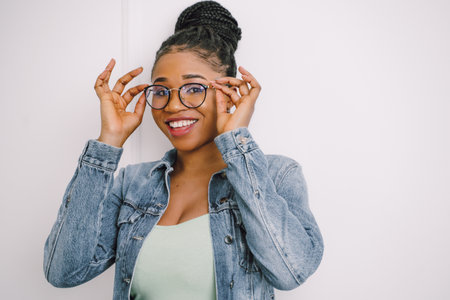 Young attractive African American woman in green dress with jean jacket and smiling in gray backgroundの写真素材