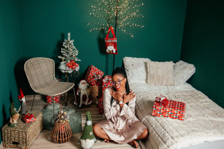 Young happy African American woman in a dress smiling and playing with Christmas decorationの写真素材
