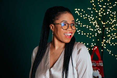 Young happy African American woman in a dress smiling and playing with Christmas decorationの写真素材