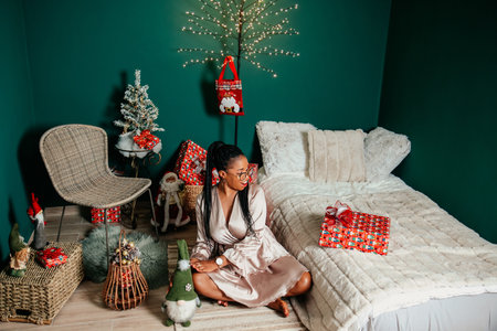 Young happy African American woman in a dress smiling and playing with Christmas decorationの写真素材