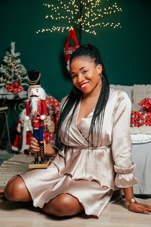 Young happy African American woman in a dress smiling and playing with Christmas decorationの写真素材