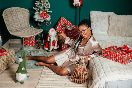Young happy African American woman in a dress smiling and playing with Christmas decorationの写真素材
