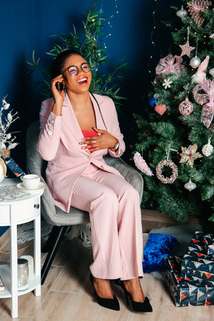 Cheerful young black woman sitting and on phone call smiling on white backgroundの写真素材