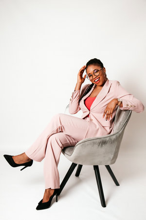 Cheerful young black woman sitting and smiling on white backgroundの写真素材