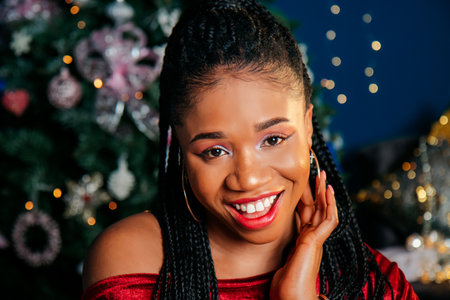 Portrait of happy young black woman in red dress on Christmas decorated backgroundの写真素材