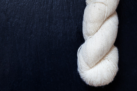 skein of yarn natural white with black slate backgroundの写真素材