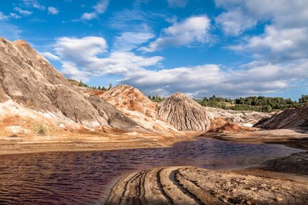 Eroded clay hills in abandoned quarry against blue sky
