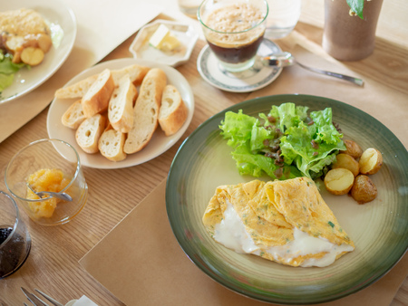 Delicious Breakfast with Omelette, Coffee ,Roasted Potatoes and Organic Salad in The White Plate and Crispy French Slice Bread, Jam on Wooden Table in The Morningの写真素材