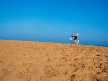Vietnamese Hawker Walking in Sand Dunes, Poppular Travel in Mui Ne, Vietnam on Sunny Dayの写真素材