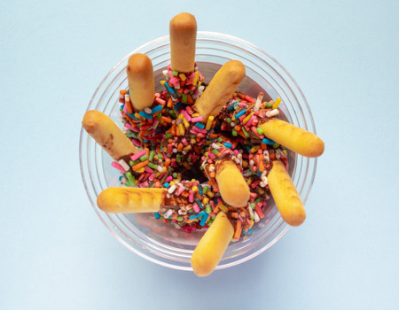 Bread Sticks with Chocolate and Colorful Topping in The Plastic Glass with Space on Light Blue Background for Fun Party Concept, Top Viewの写真素材