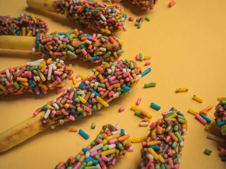 Close-up Bread Sticks with Chocolate and Colorful Topping with Space on Yellow Light Background for Fun Party Conceptの写真素材
