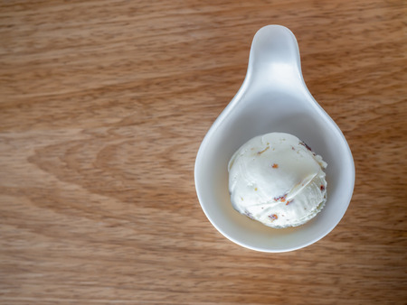 Scoop of Homemade Rum Raisin Ice Cream in Little White Cup on Wooden Backgroundの写真素材