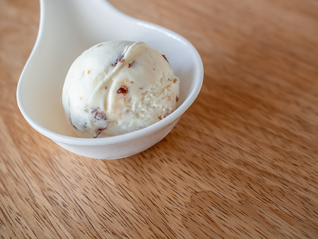 Scoop of Homemade Rum Raisin Ice Cream in Little White Cup on Wooden Backgroundの写真素材