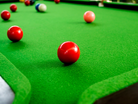 Red and Colorful Snooker Balls Near Corner Hole on Green Snooker Tableの写真素材