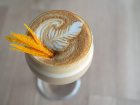 Cappuccino Romano Coffee Topping with Lemon or Orange Slice in Glass on Wooden Table Backgroundの写真素材