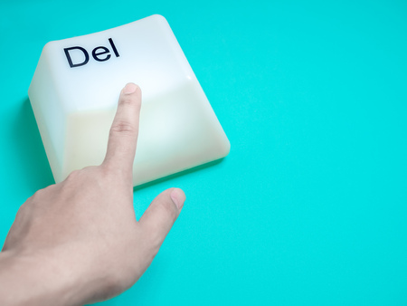 Finger is Pressing Big Delete Computer Key Button Light Box Isolated on Aqua Blue or Green Background with Space. Eraser Concept.の写真素材