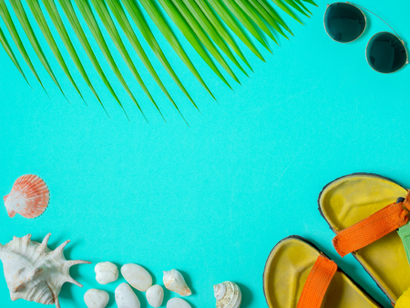 Flat Lay Traveler Accessories, Colourful Sandal, Sunglasses with Beach Seashells, Beach Pebbles and Coconut Palm Leaf on Aqua Blue Background with Blank Text Space. Top View Vacation Summer Concept.の写真素材