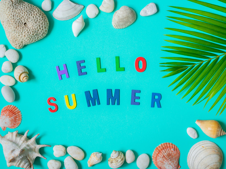 Flat Lay Beach Accessories, Hello Summer Colorful Text, Beach Seashells, Coral, Beach Pebbles and Coconut Palm Leaf on Aqua Blue Background. Top View Vacation Summer Concept.の写真素材