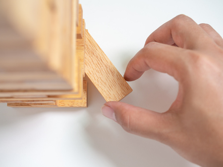 Hand Move out The Block Playing Tumble Tower Wooden Block Game on White Background. Business Conceptの写真素材