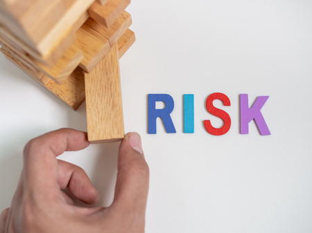 Hand Move out The Block Playing Tumble Tower Wooden Block Game with Risk Colorful Text on White Background. Business Conceptの写真素材