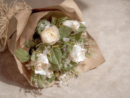 Artificial White Roses Bouquet in Wrapping Brown Craft Paper on Concrete Backgroundの写真素材