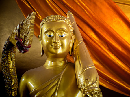 The Golden Buddha Monk Looking Down and Smiling Holding Umbrella near The Golden Serpent on Yellow Robe Backgroundの写真素材