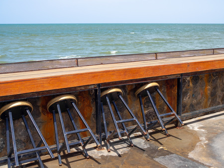 Wooden Counter Bar Table and Chairs on Blue Sky and Seascape Background with Space.の写真素材