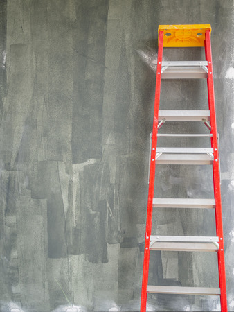 Construction Building Area with Standing Red Ladder on Concrete Wall Background with Copy Space.の写真素材